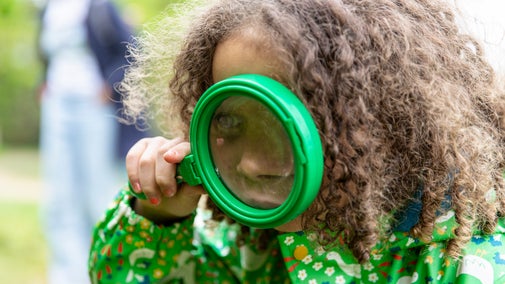 A little girl looking through a magnifying glass